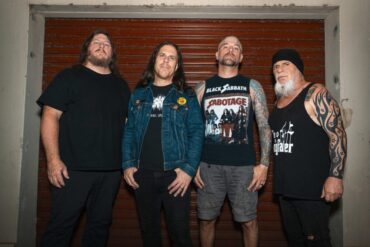 Vier Metal Musiker vor einer Garage, lässig posierend.