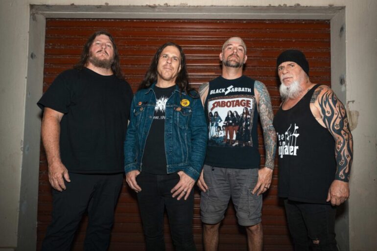 Vier Metal Musiker vor einer Garage, lässig posierend.
