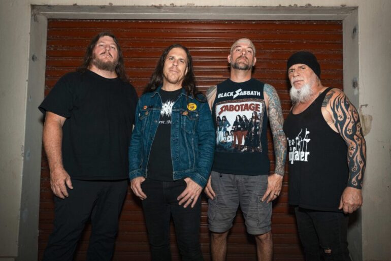 Vier Metal Musiker vor einer Garage, lässig posierend.