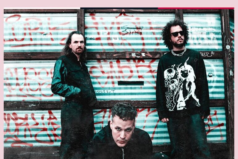 Bandfoto von Added Color vor einem Graffiti-beschmierten Hintergrund.