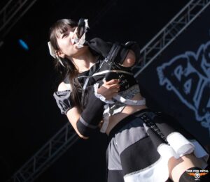 Metal Sängerin bei Time For Metal Konzert mit Mikrofon und Bühnenlicht.
