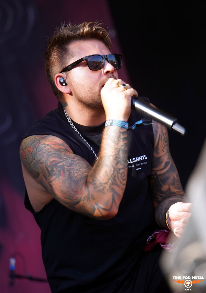 Metal Sänger mit Sonnenbrille singt live auf der Bühne.