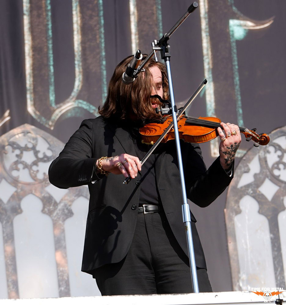 Musiker spielt Geige bei Metal-Konzert auf Bühne.