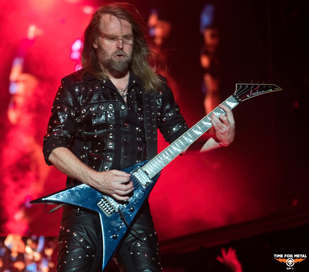 Metal Gitarrist spielt auf der Bühne mit rotem Licht im Hintergrund.