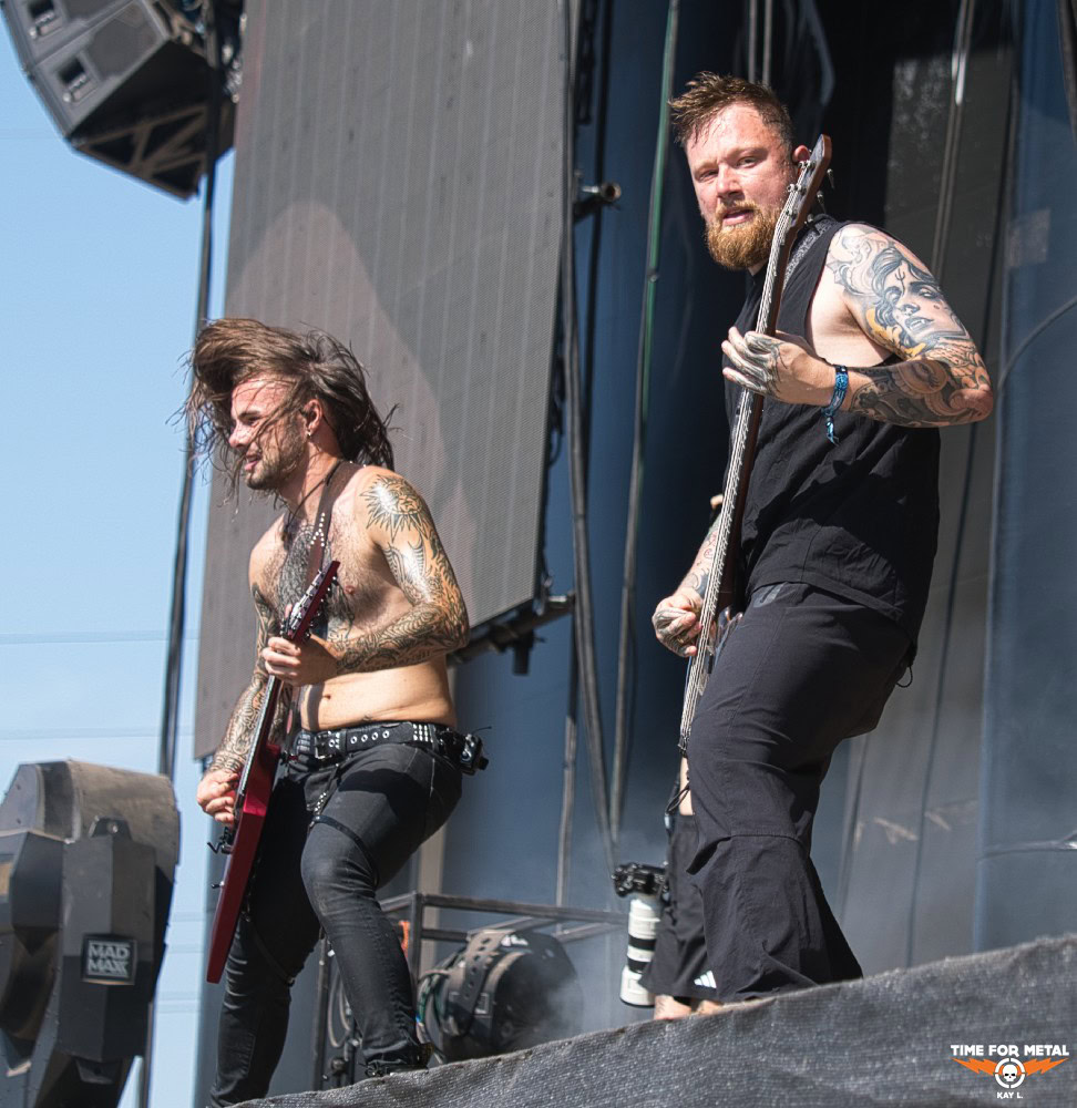 Zwei Gitarristen mit Tattoos spielen auf der Bühne bei einem Metal-Festival.
