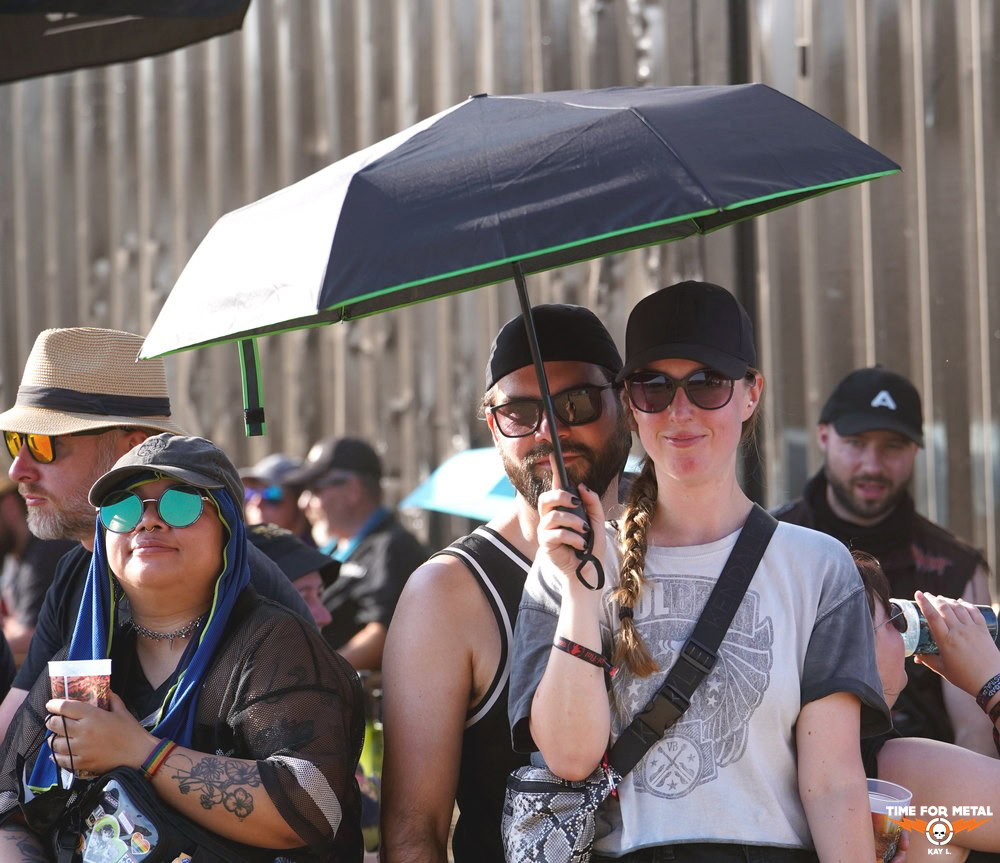 Menschen bei Metal Festival mit Regenschirm und Sonnenbrillen.