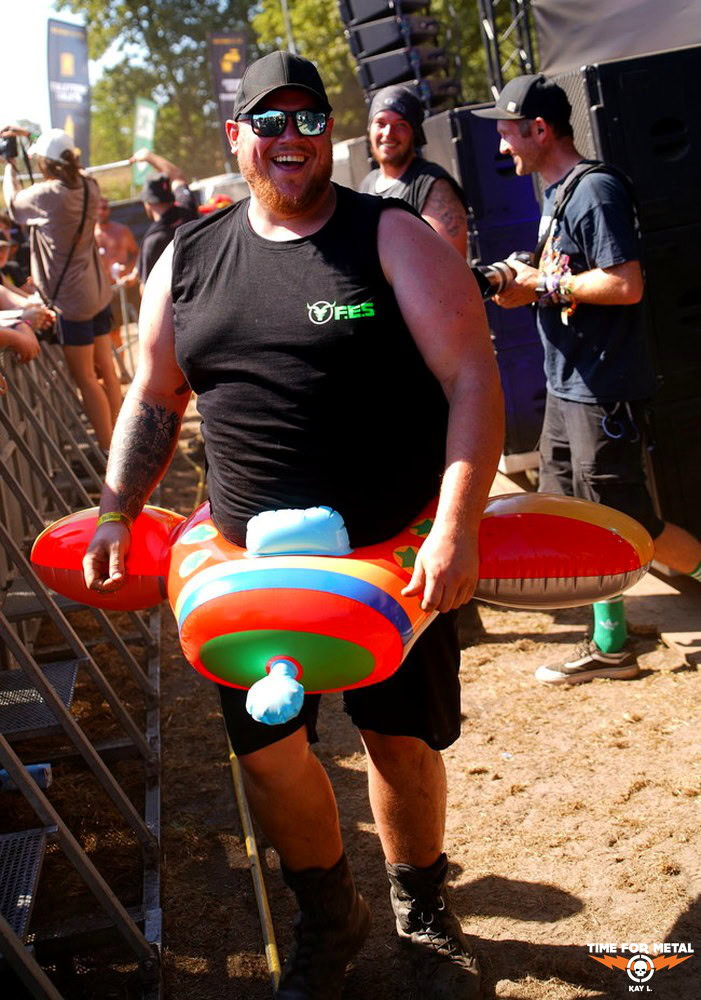 Fröhlicher Mann mit aufblasbarem Metal-Logo im Freien bei Festival.