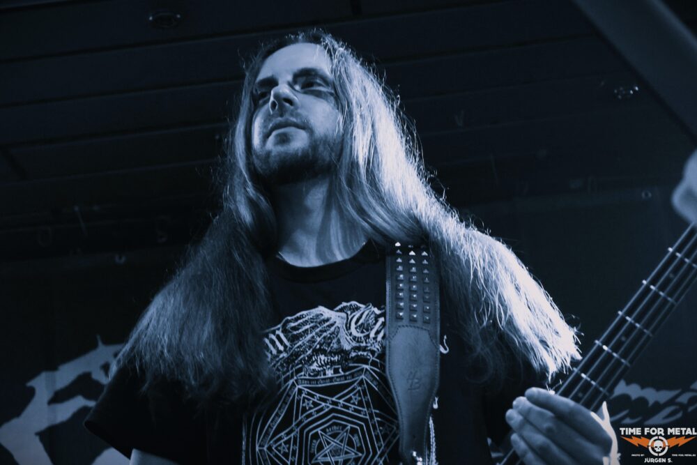 Metal Gitarrist mit langem Haar und E-Gitarre auf Bühne.